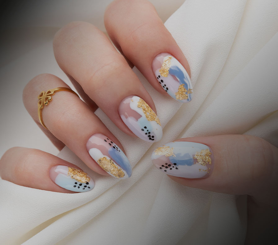 Die Nägel einer Frau mit goldenen und blauen Mustern aus einem Nagelstudio.
